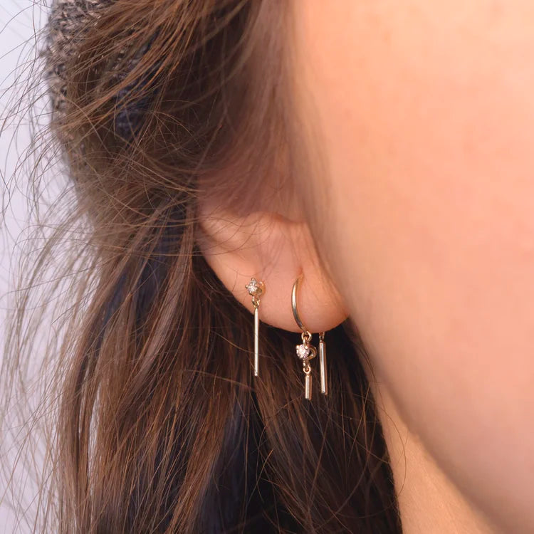 Diamond Wisp 14k gold stud earring stacked on ear in a delicate layered style.