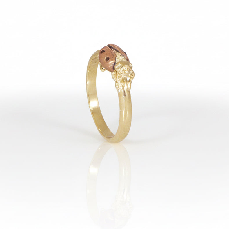 Side view of a handmade 14k gold ladybug ring highlighting the raised insect design, textured yellow gold details, and polished ring band.