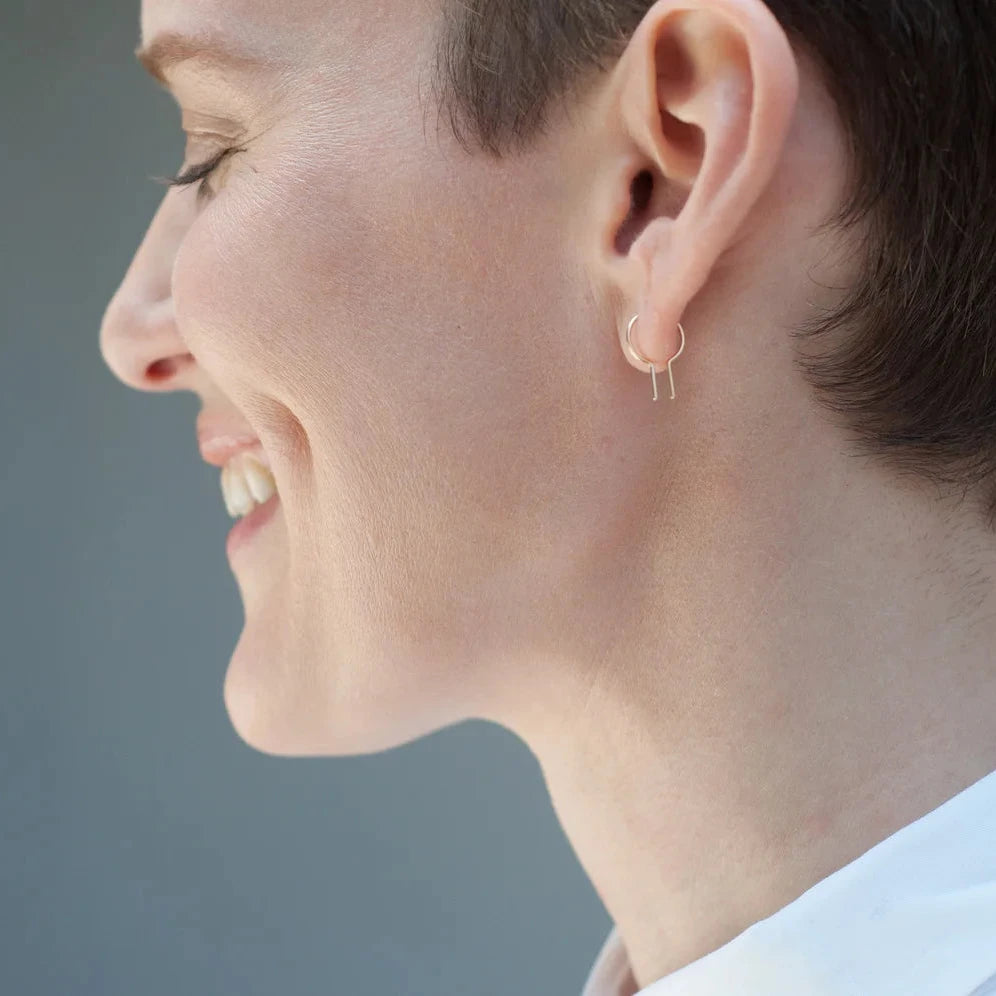 Side view of a person wearing a 14k gold Loopdie minimalist single earring.