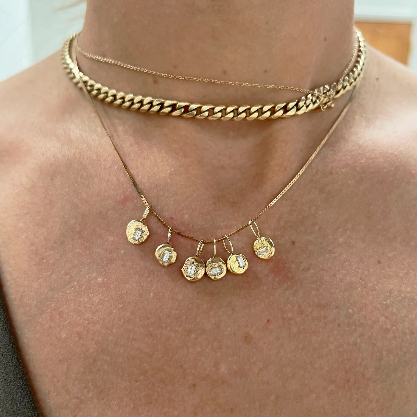 Gold chain necklace with gold pendants on a person's neck