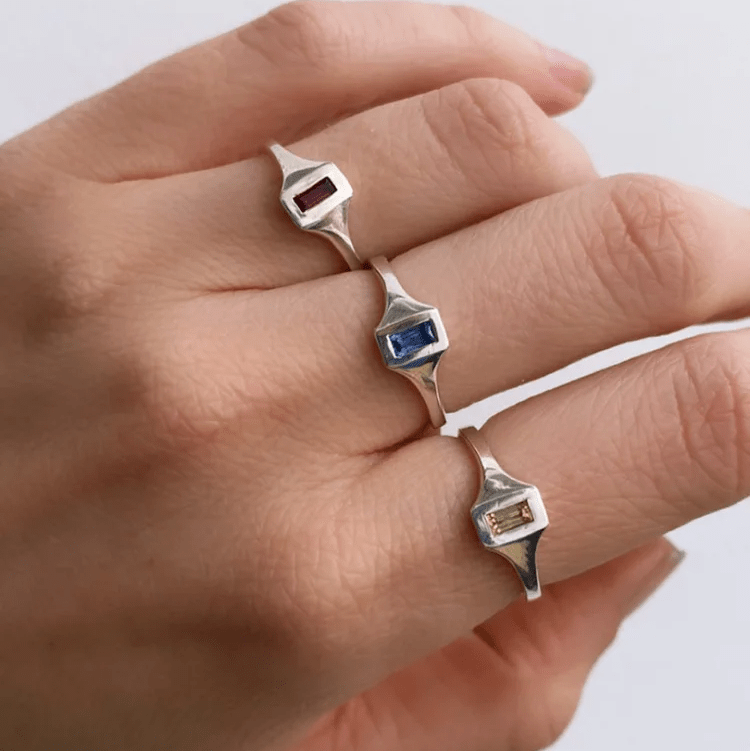 Sterling silver Passage Rings with garnet, sapphire, and citrine baguettes worn on a hand in natural light.