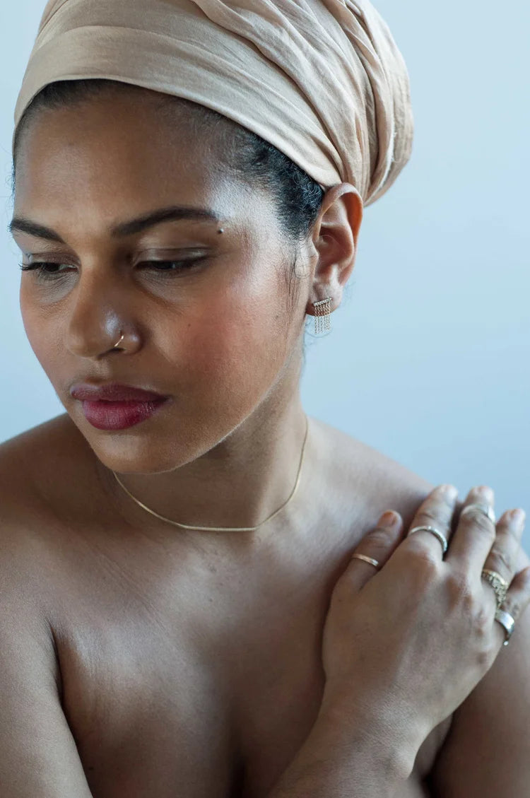Model wearing a short 14k gold fringe earring with pavé detail, photographed in soft natural light.