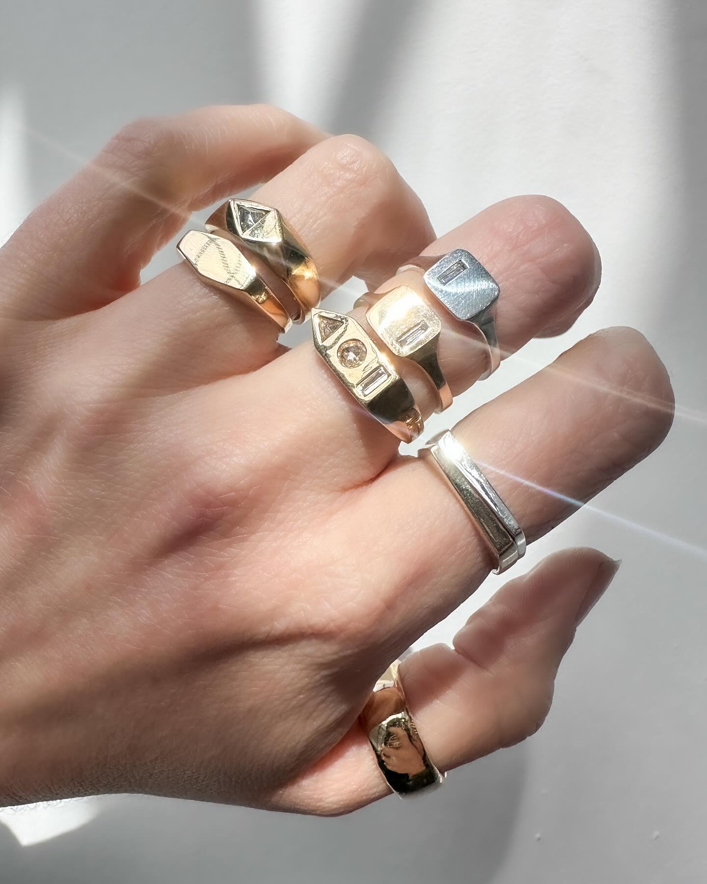 Hand wearing the sterling silver tapered band stacked with other rings in natural light.