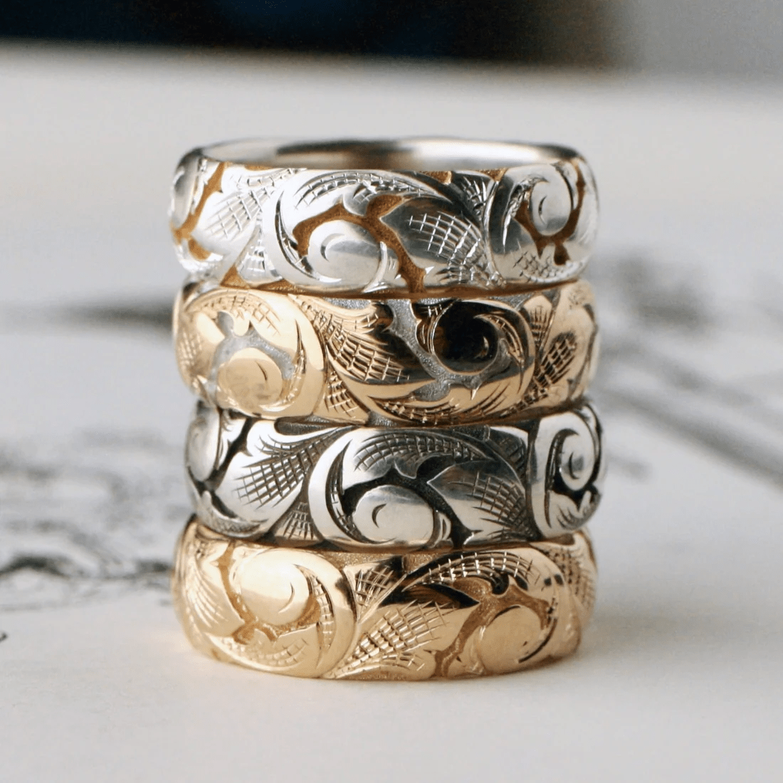 Stacked slim acanthus engraved bands in silver, two-tone, and gold.