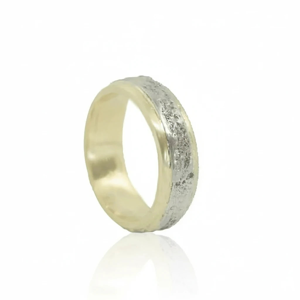 Angled view of the Two Tone Breccia Metamorphic Band by Alexis Pavlantos, featuring a hand-carved 14k white gold exterior with organic rock texture and a smooth 14k yellow gold interior.