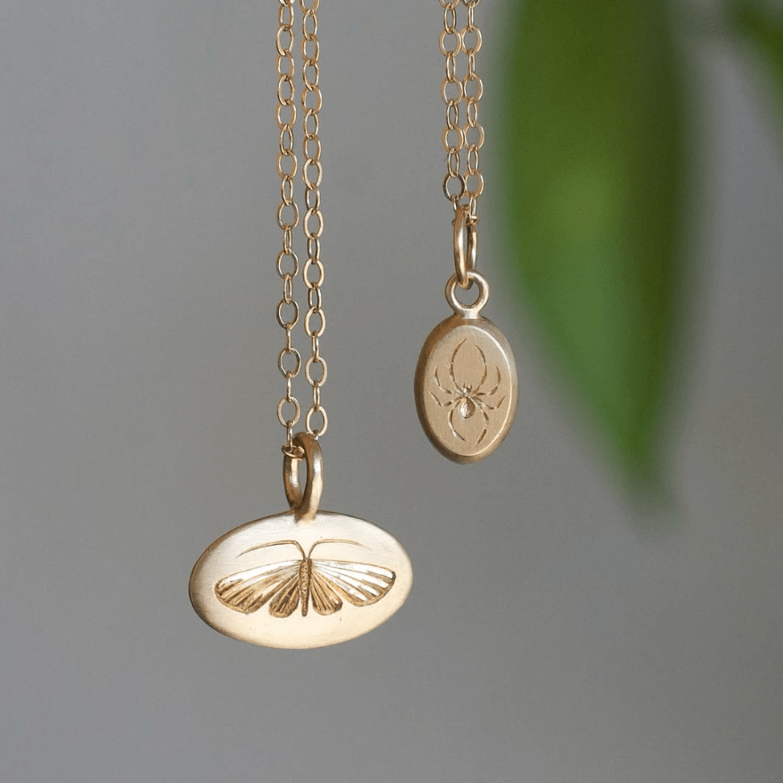 14k gold hand-engraved house moth pendant hanging from a delicate chain.