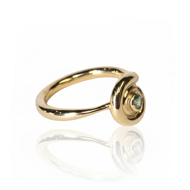 Angled view of the 14k yellow gold Spiral Sapphire Ring showing its curved open spiral band and round teal sapphire in a raised circular setting.