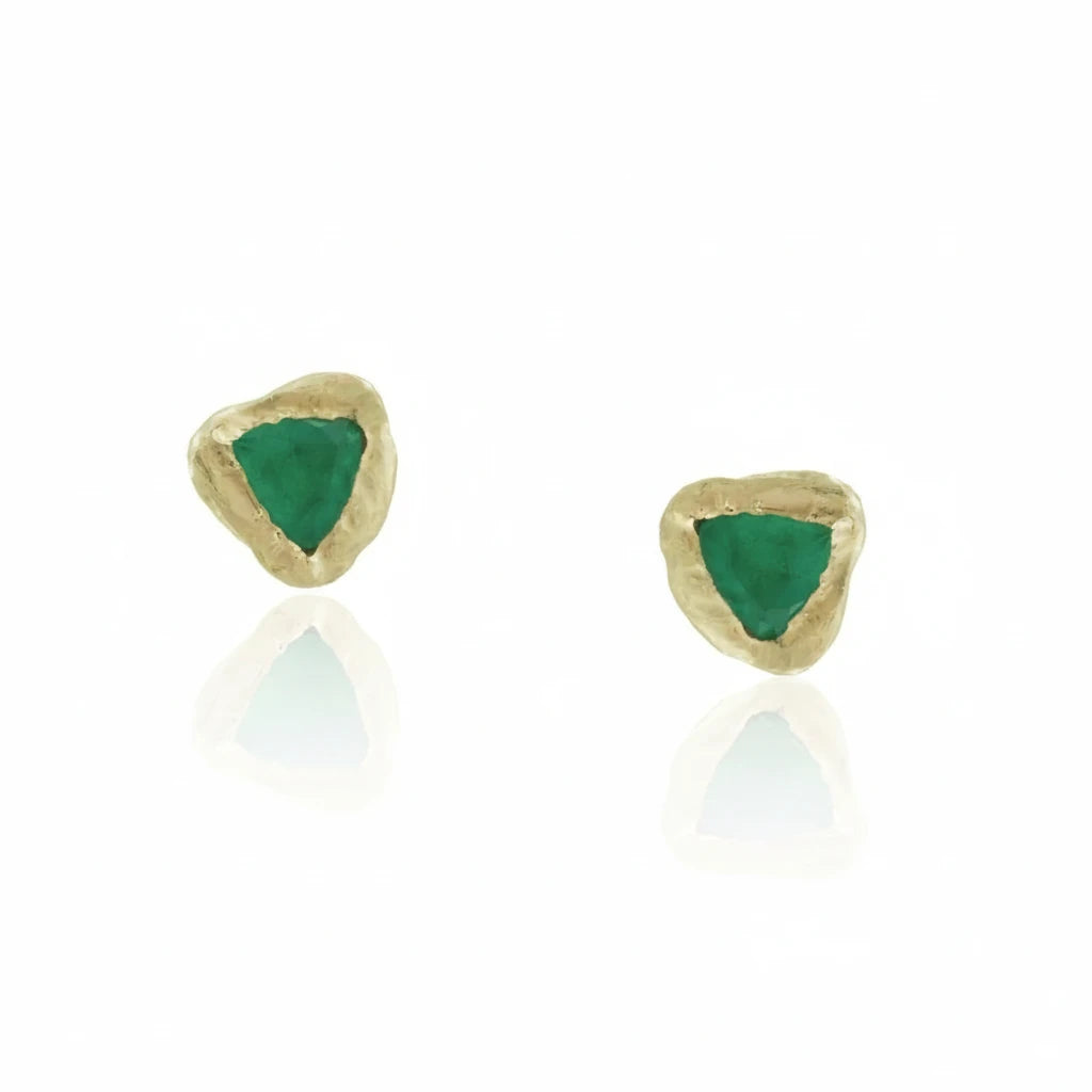 Pair of sculptural 14k yellow gold emerald stud earrings featuring vivid green trillion-cut emeralds in hand-carved, Petra-inspired settings.