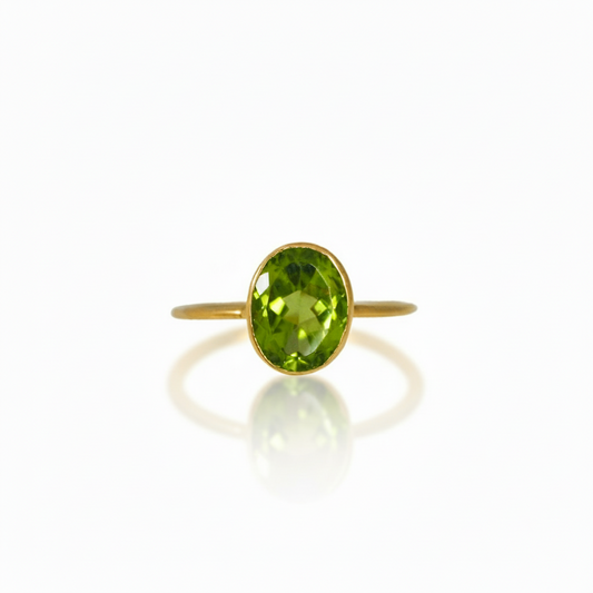 An 18k yellow gold ring with a faceted peridot stone set vertically on a minimalistic band.