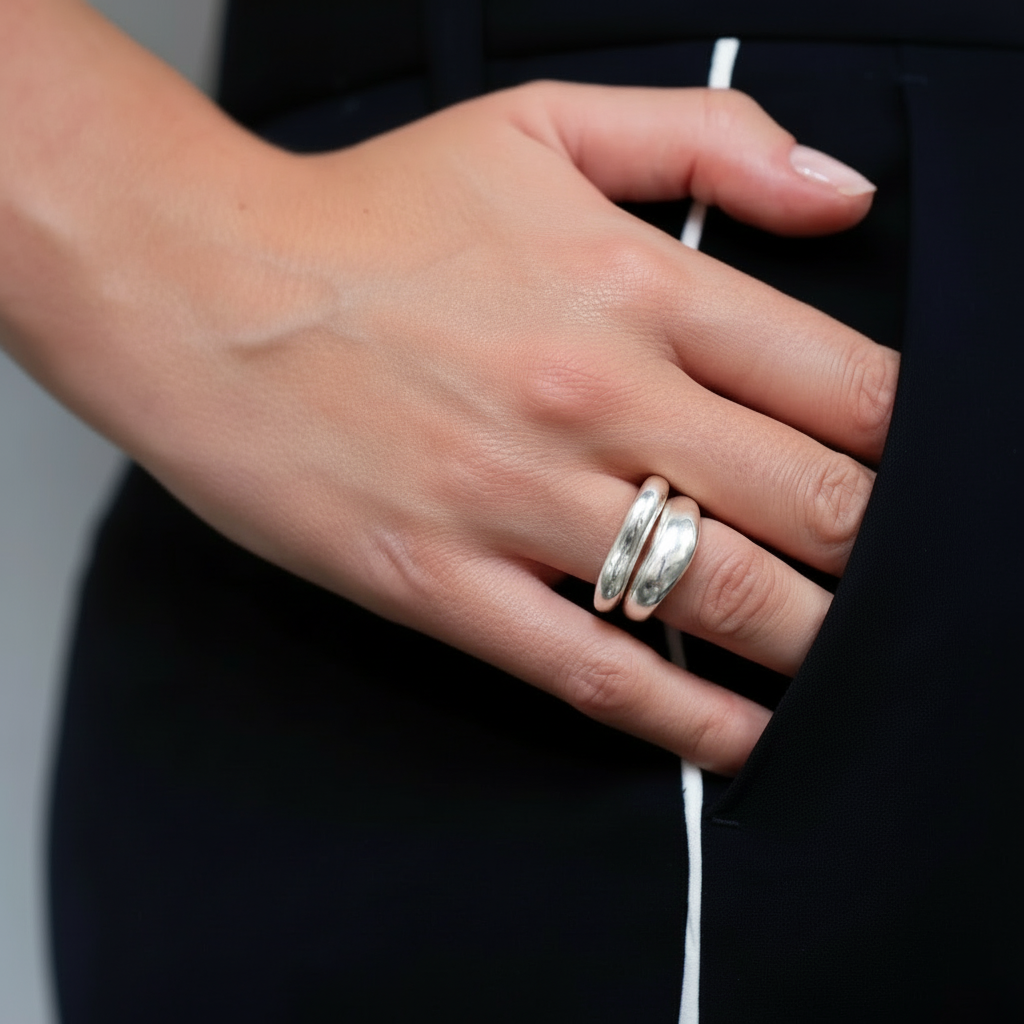 Hand wearing silver rings with a blurred background