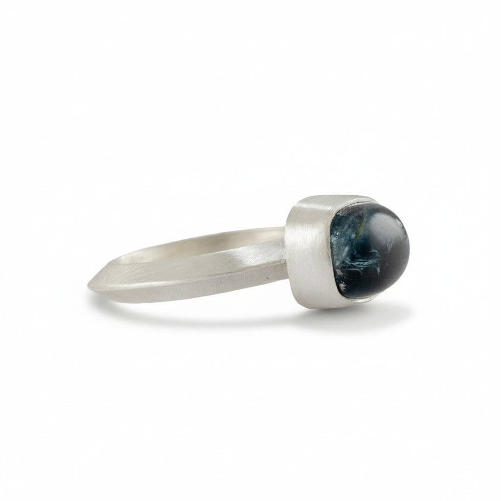 Silver ring with a dark blue stone on a white background