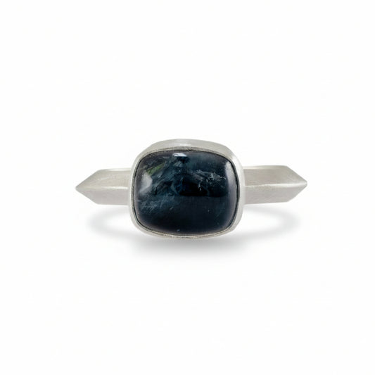 Silver ring with a central dark blue tourmaline stone on a white background