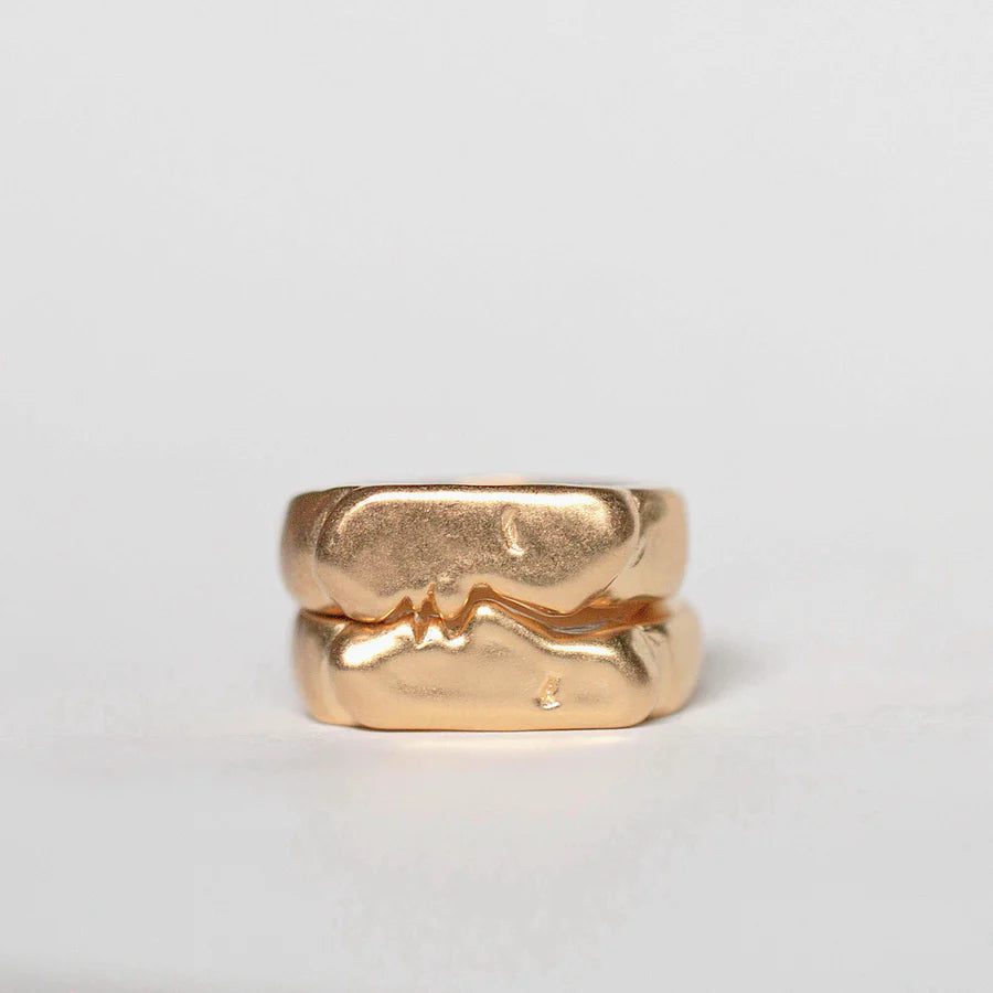 Two gold-plated sterling silver kiss signet rings, displayed against a light background.