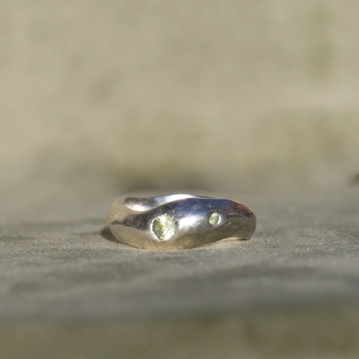 Silver ring with two small stones on a beige background