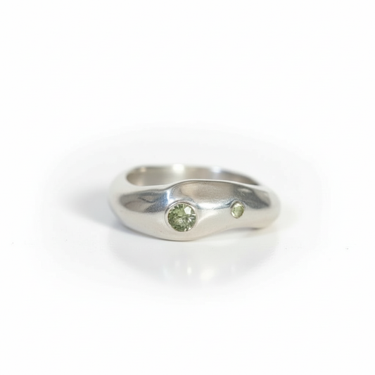 Silver ring with two green gemstones on a white background