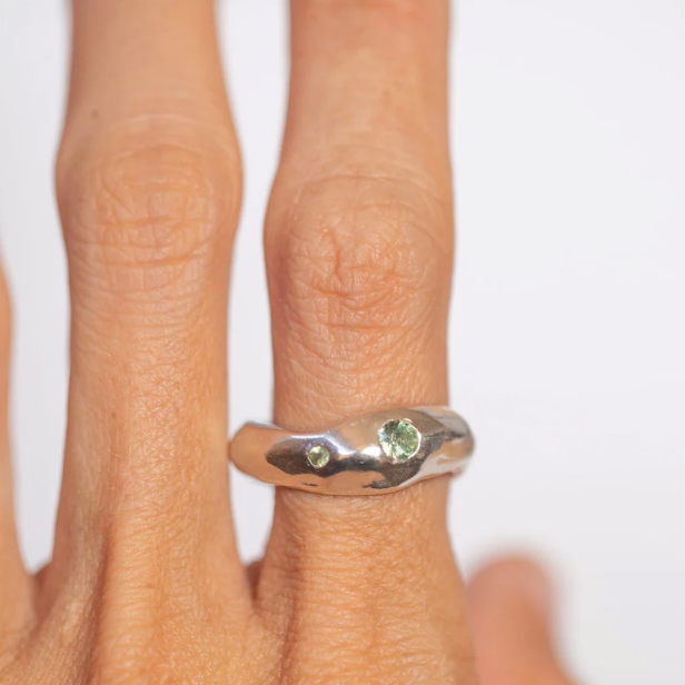 Silver ring with sapphire and Peridot on a white background worn on finger