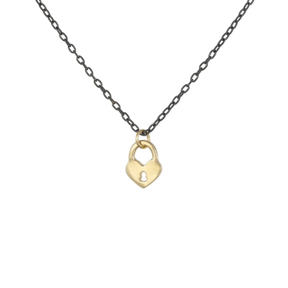 Gold heart-shaped lock pendant on an oxidized silver chain, Tiny Heart Lock Necklace by Luana Coonen, shown on white background.