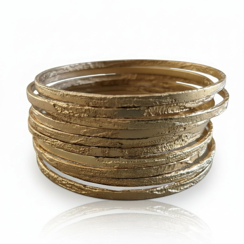 Stack of thin etched bangles in 22k gold-plated brass displayed on a white background.