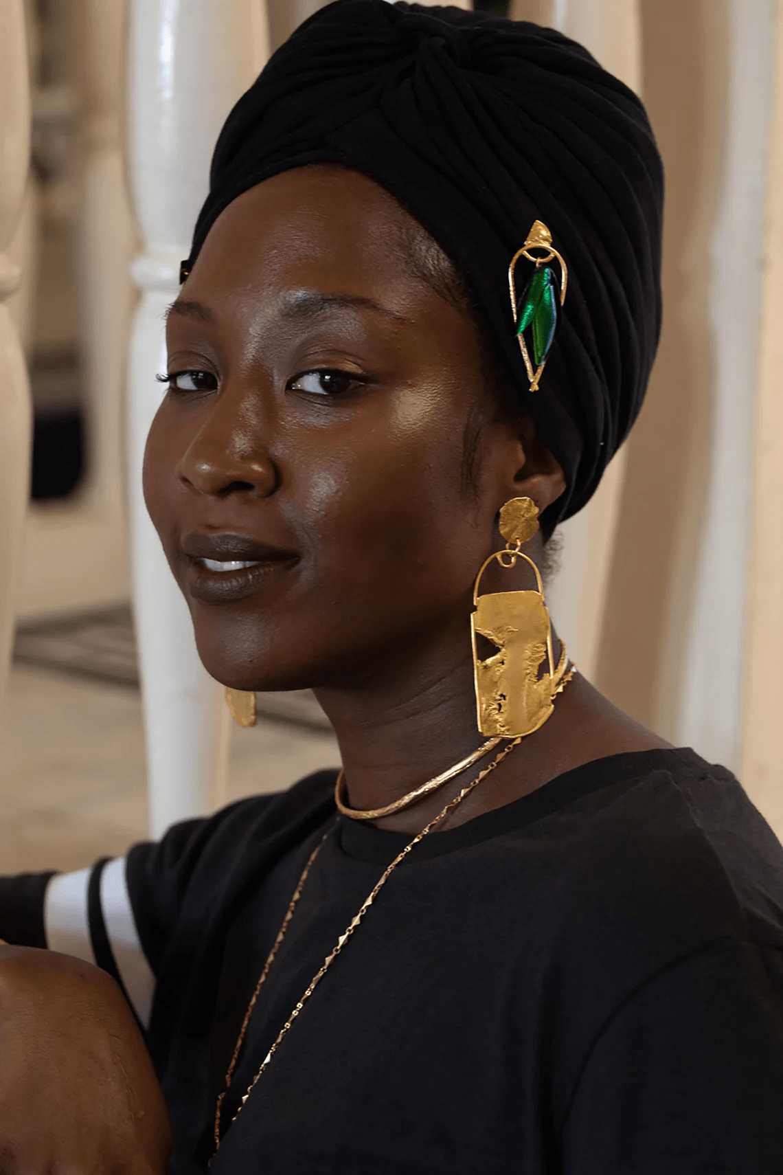 Model wearing green beetle wing earrings with gold-plated brass, shown in an indoor portrait.