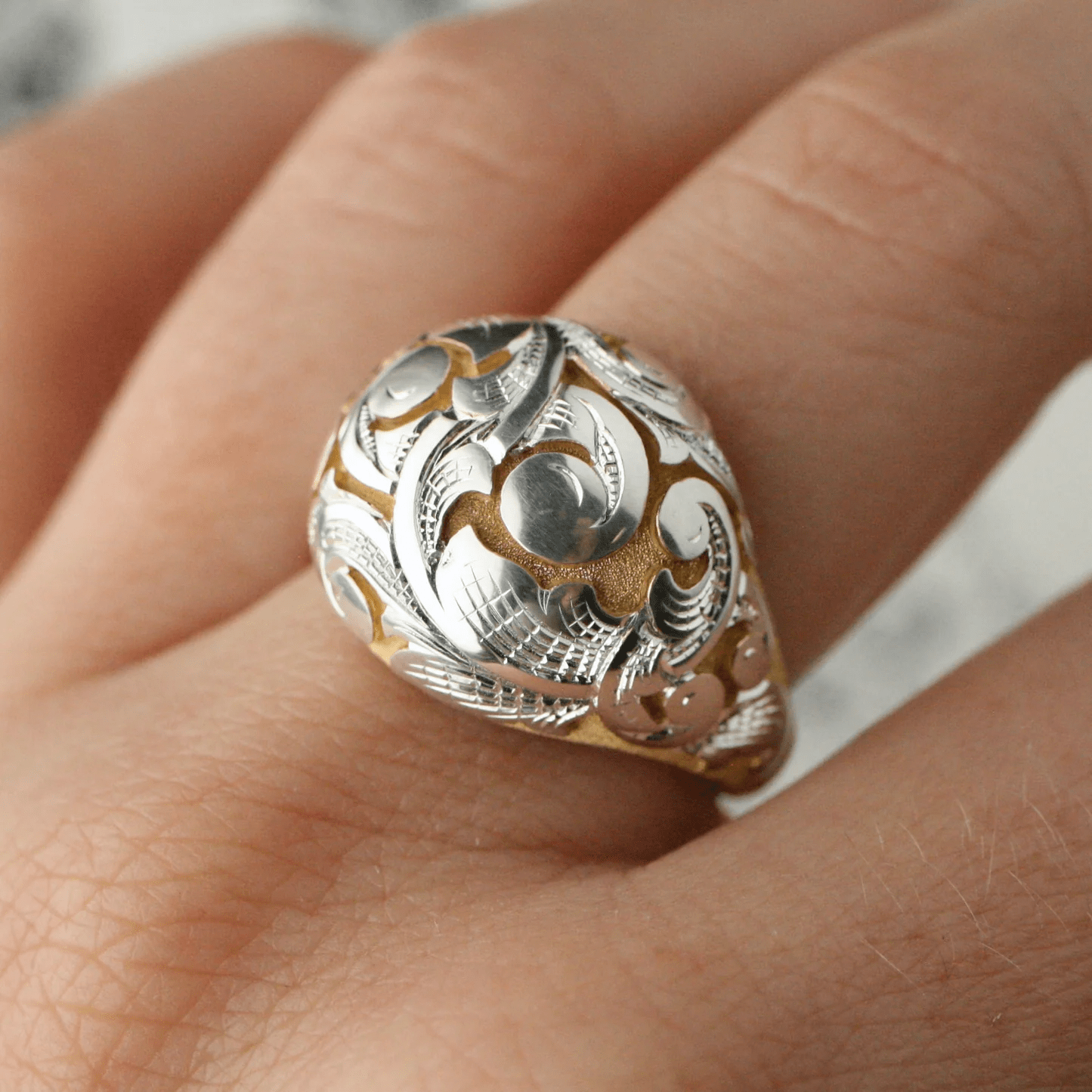 Acanthus Bombe Ring in silver with gold scrollwork worn on finger, side perspective.