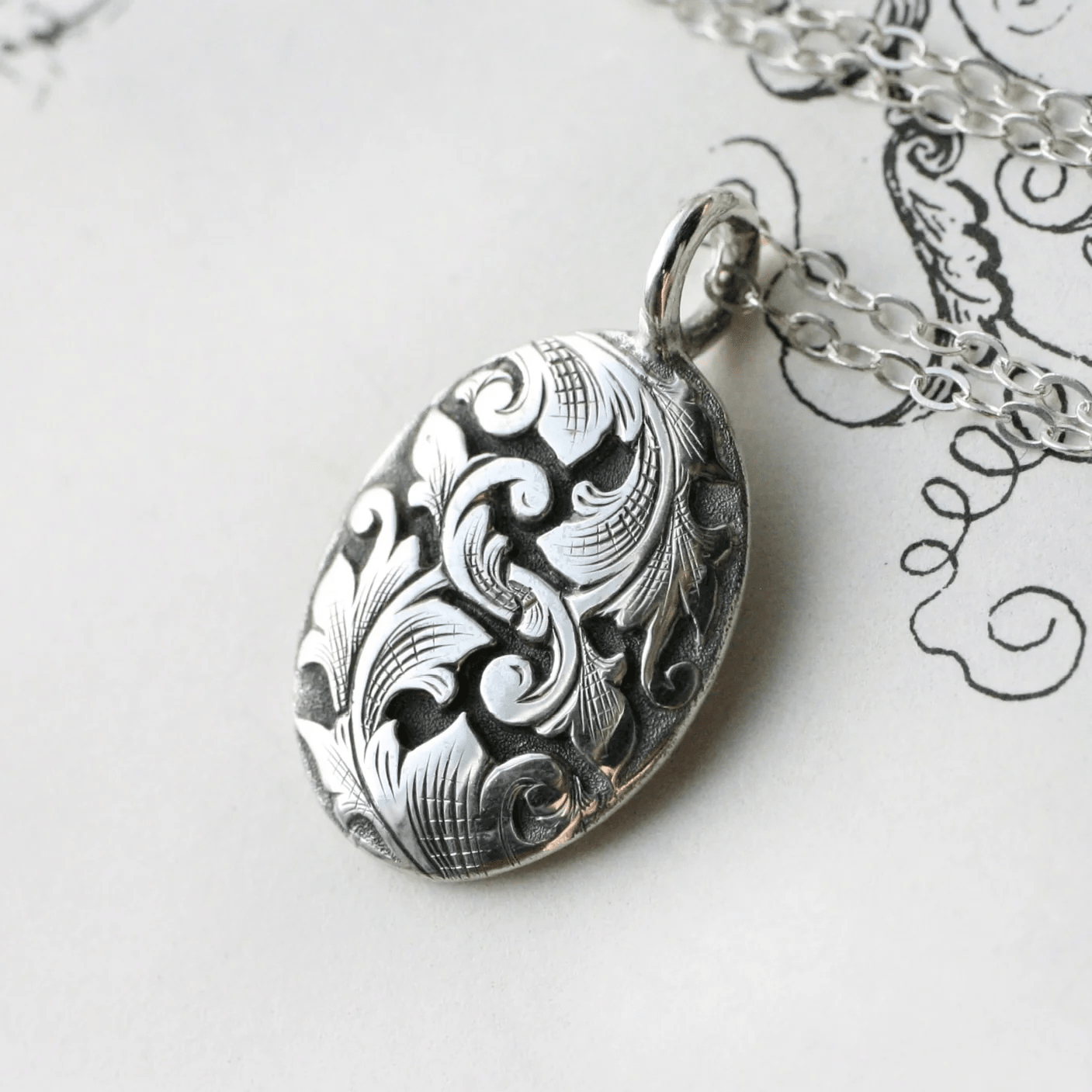 Close-up of the hand-engraved sterling silver Acanthus oval pendant by Blue Blue Driver on an 18-inch chain.