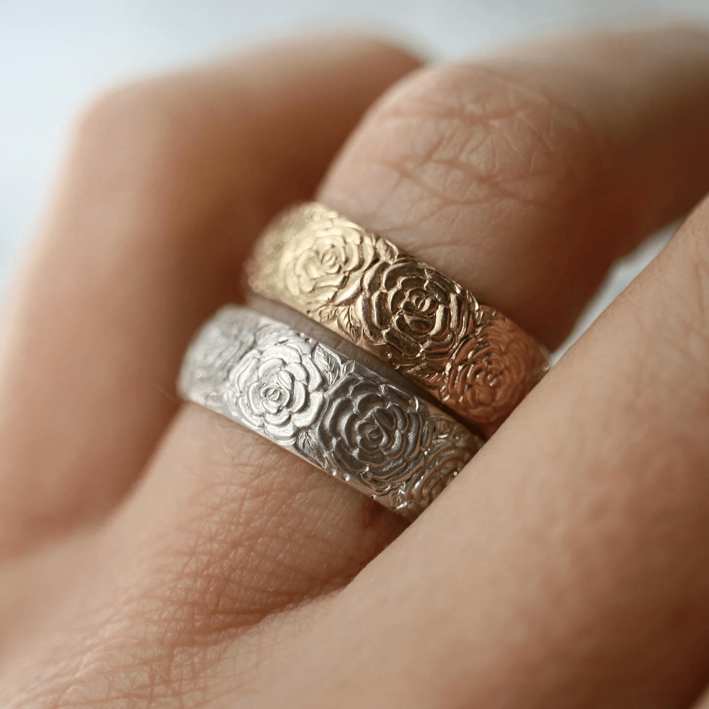 Stacked sterling silver and 14k gold beloved Rose band rings by Blue Blue Driver worn together on hand.
