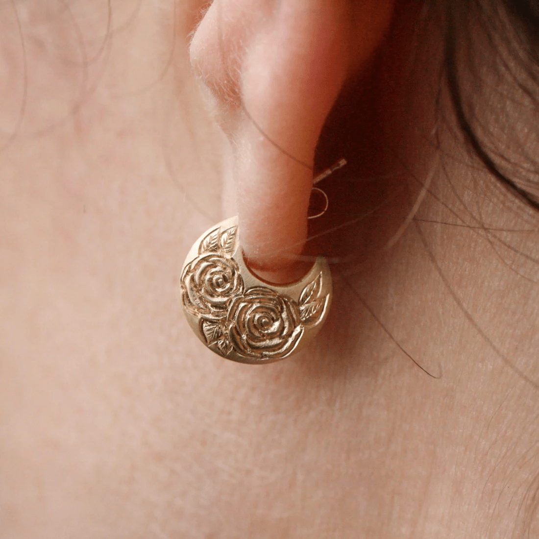 Close-up of the hand-engraved 14k gold Beloved Rose earrings by Blue Blue Driver worn on the ear.