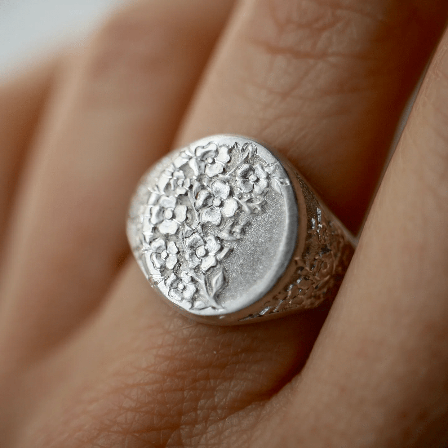 Sterling silver Dogwood signet ring worn on a finger, showing the detailed floral engraving.
