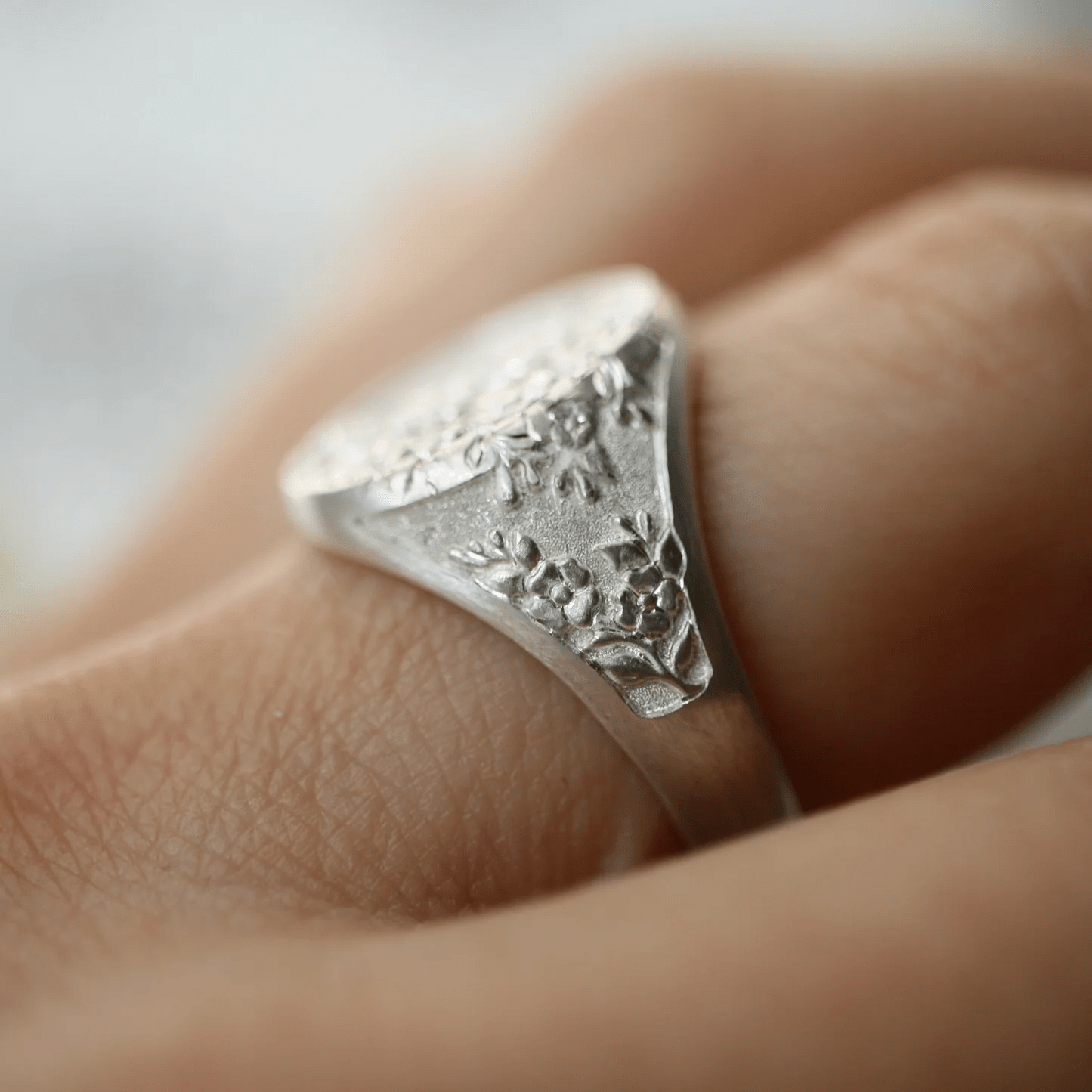 Side view of the sterling silver Dogwood signet ring worn on a hand, highlighting the engraved texture.