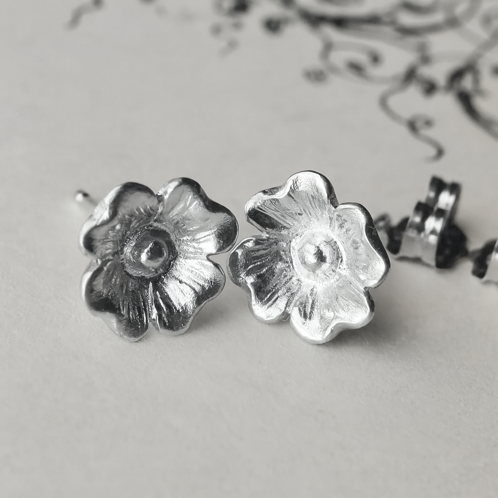 Silver dogwood flower stud earrings shown in a close-up display.