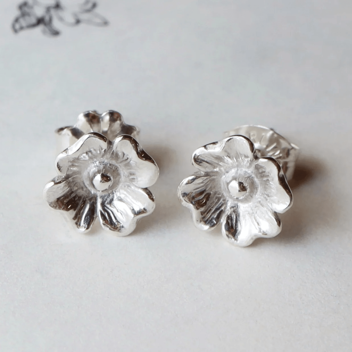 Silver dogwood flower stud earrings shown from the front in a display setting.