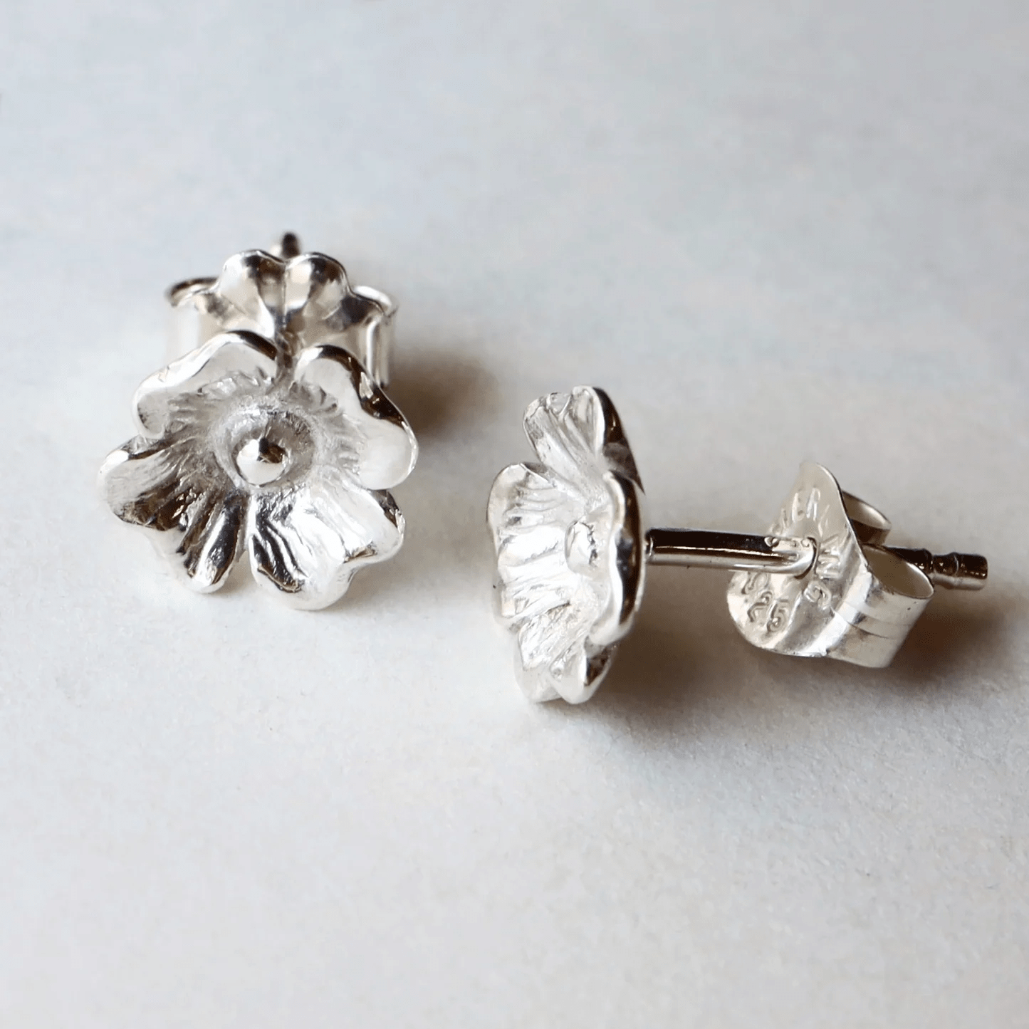 Side display of silver dogwood flower stud earrings.