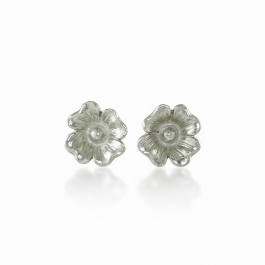 Pair of silver dogwood flower stud earrings on a white background