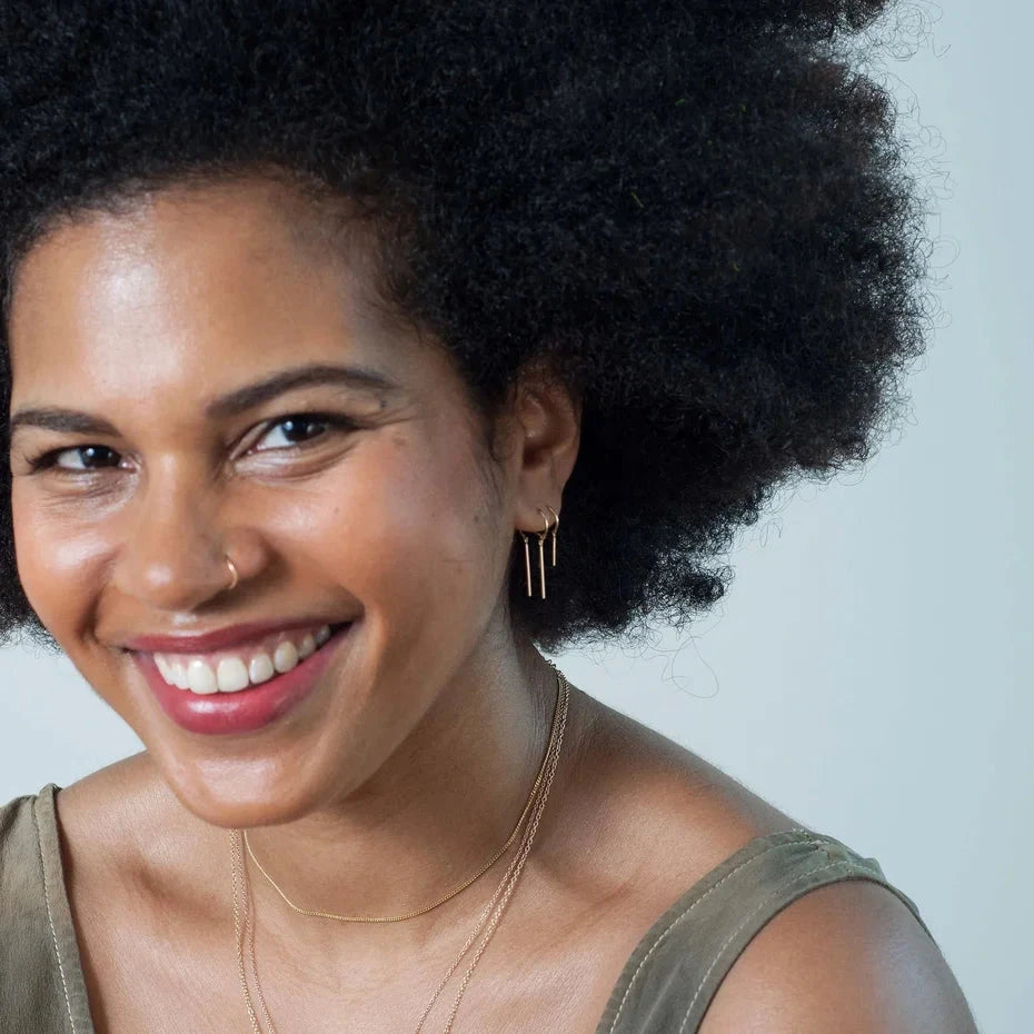 Model wearing the 14k gold Chime Earring, minimalist dangling design.