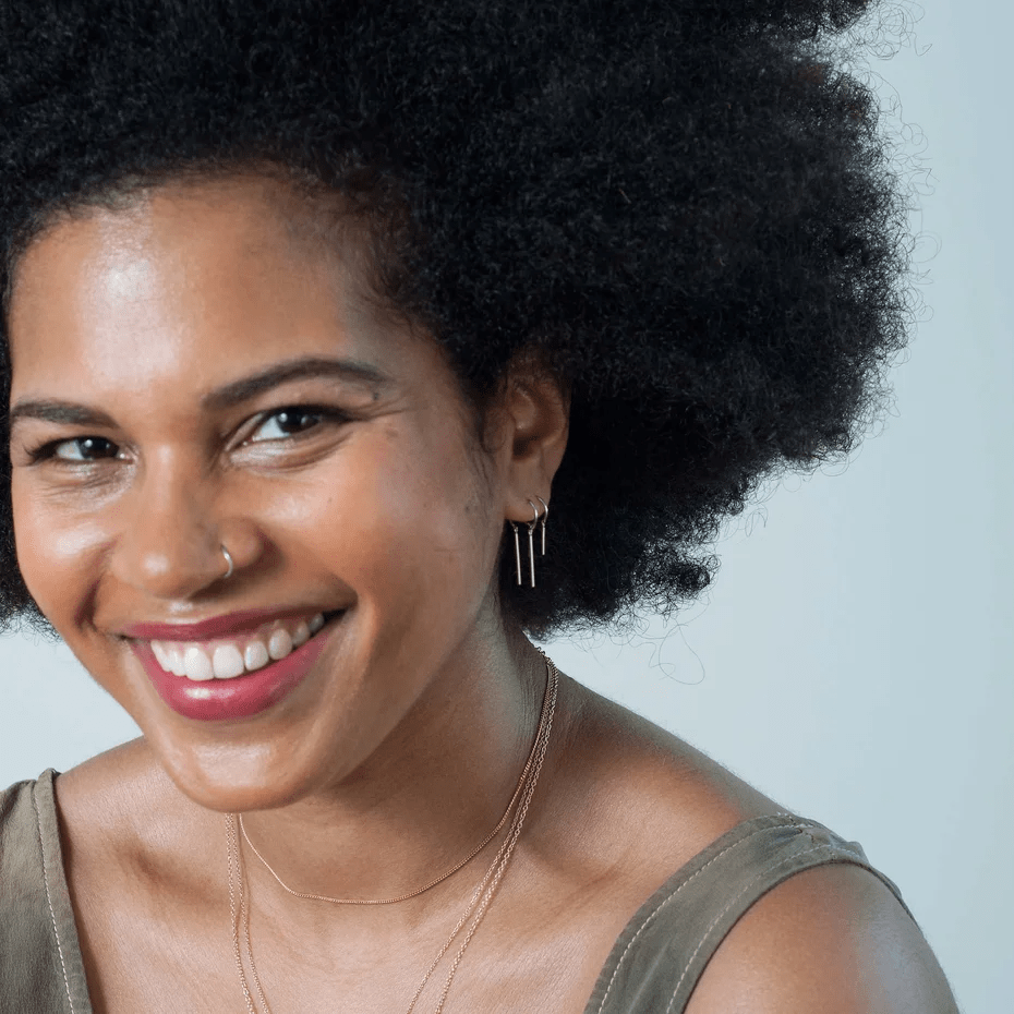 Model smiling while wearing sterling silver chime earring, showing its lightweight movement.