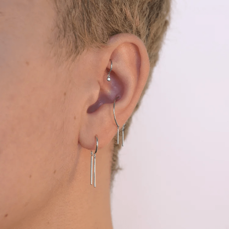 Close-up side view of sterling silver chime earring worn on the ear.