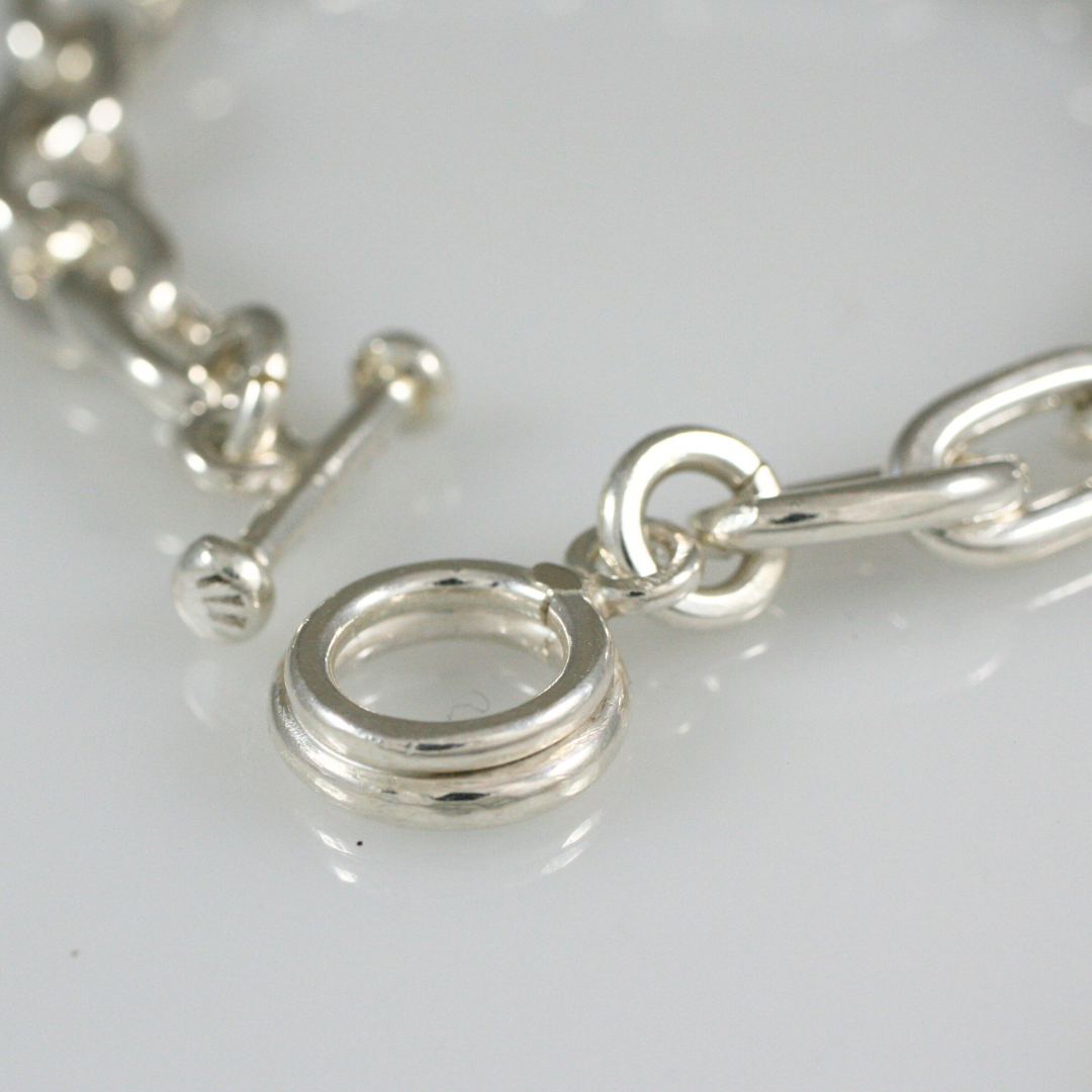 Close-up of the sterling silver toggle clasp on Lambert Eustace's chunky chain bracelet, showing the handcrafted links and closure.