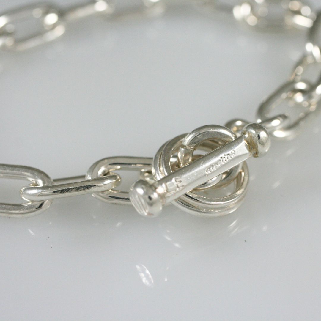 Detailed view of the oversized sterling silver chain links on Lambert Eustace's handcrafted bracelet, highlighting their organic texture and polished finish.