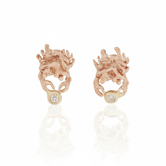 Hand-sculpted crab stud earrings in solid 14k rose and yellow gold by Alexis Pavlantos, each featuring a miniature crab holding a 1mm round white diamond.
