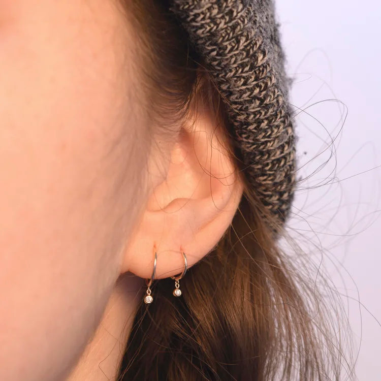 Side view of model wearing a 14k gold diamond droplet huggie earring.
