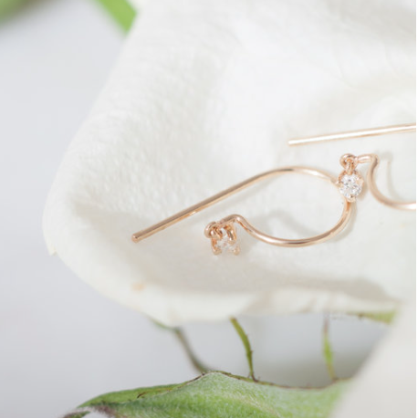 Diamond Loopdie Earring in 14k gold resting on soft white fabric – elegant lifestyle detail.