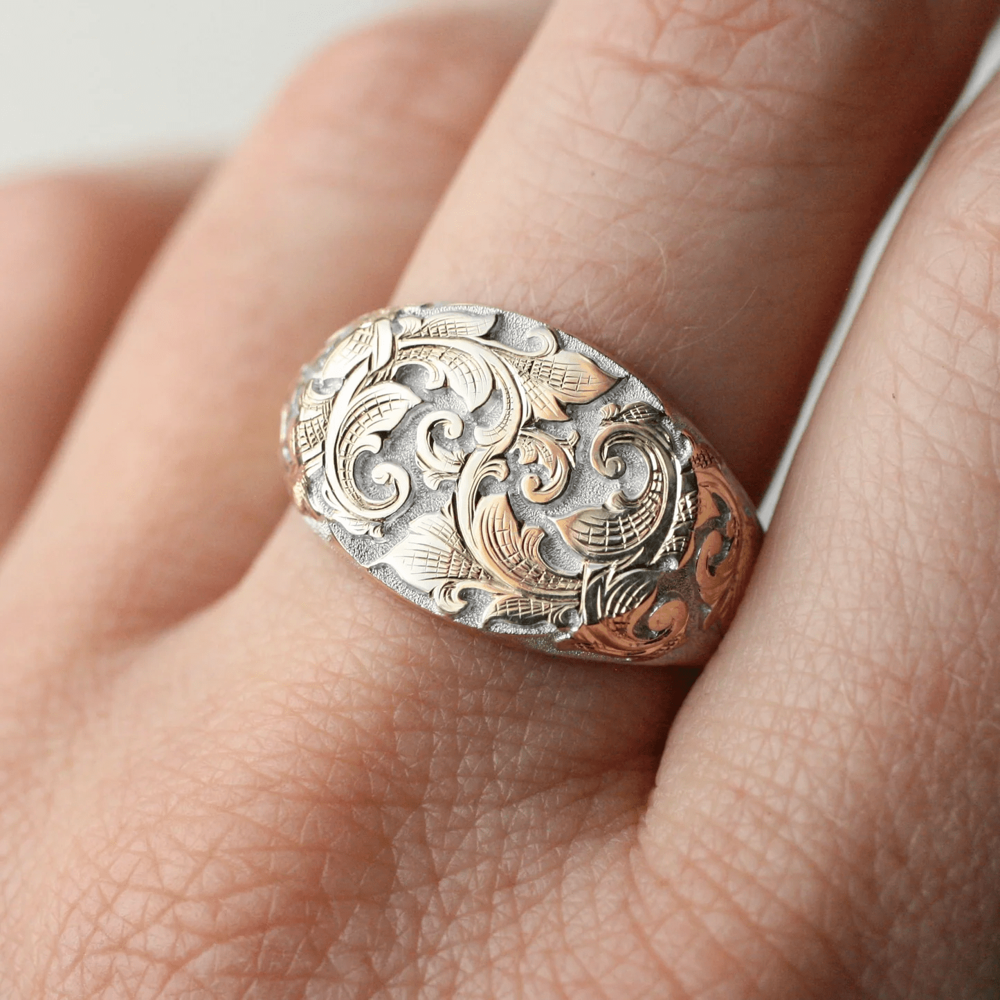 Hand view of the East-West Acanthus Signet Ring in sterling silver with gold accents.