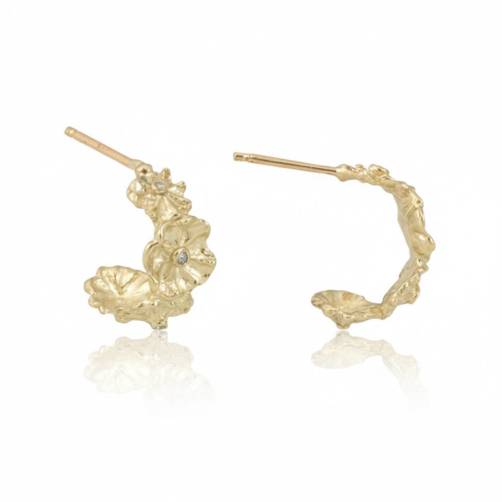 Angled view of sculptural 14k gold floral hoop earrings by Alexis Pavlantos, highlighting their intricate organic petal texture and curved hoop shape.