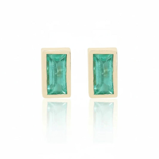 Pair of 14k yellow gold stud earrings featuring antique baguette-cut green emeralds in minimalist rectangular bezel settings.