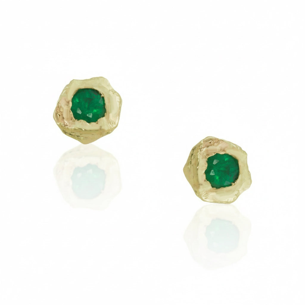 Pair of Emerald Petra Stud Earrings by Alexis Pavlantos, featuring 3mm round brilliant-cut emeralds set in hand-carved 14k yellow gold with organic rock texture.