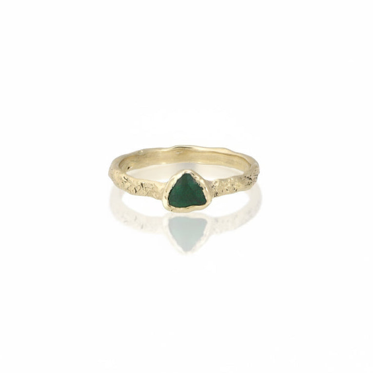 Emerald Trillion Metamorphic Ring by Alexis Pavlantos, featuring a 0.30 carat trillion-cut green emerald in a sculptural rock-textured 14k yellow gold band.