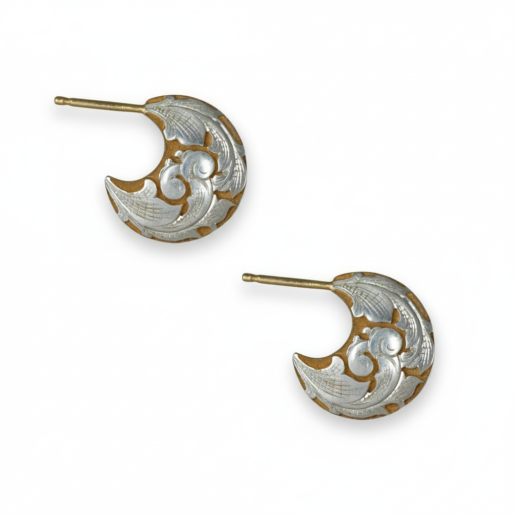 Pair of two-tone engraved crescent earrings on white background – scroll and leaf motif.