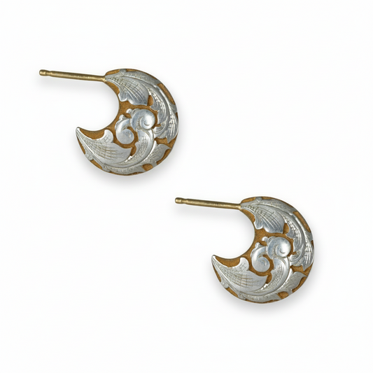 Pair of two-tone engraved crescent earrings on white background – scroll and leaf motif.