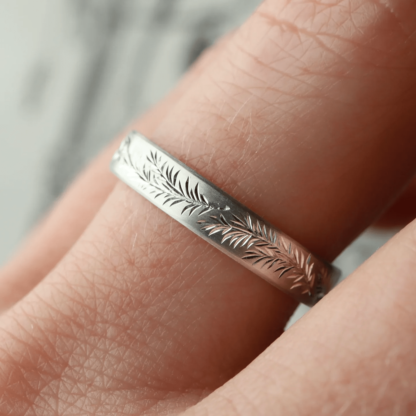 Sterling silver engraved rosemary band worn on finger – fine leaf engraving.