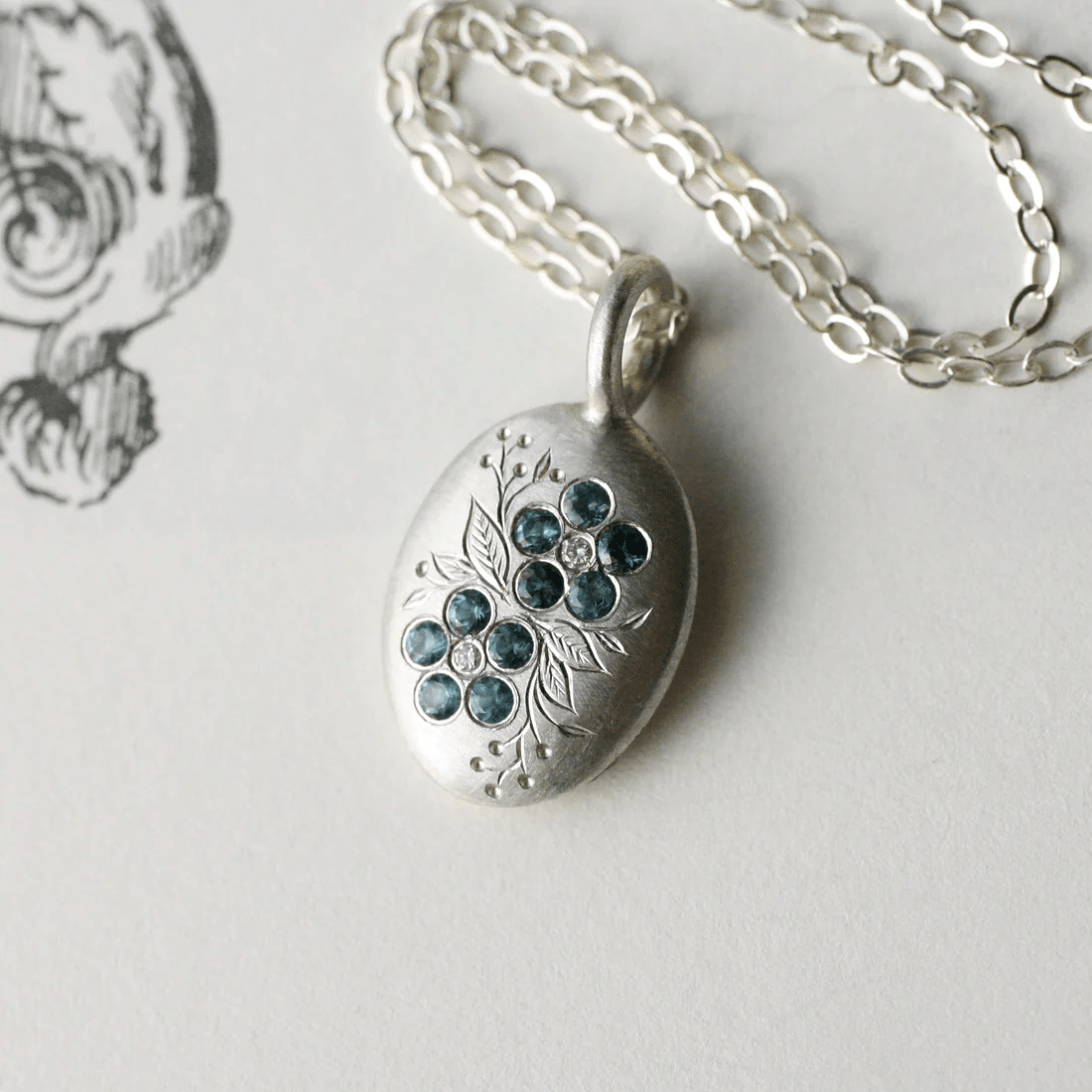 Sterling silver forget-me-not pendant with London blue topaz stones on a fine silver chain.